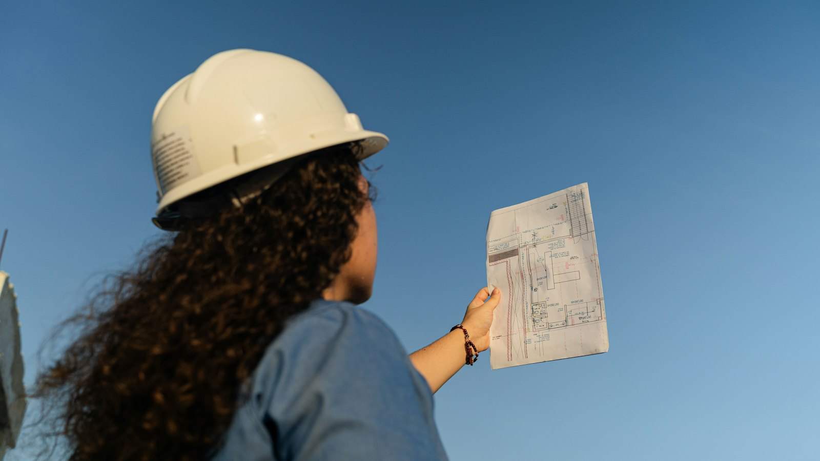 Surveyor in a hard hat checking plans on site